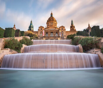 Long-exposure photo of the Montjuïc Magic Fountain cascading in soft tiers beneath the Palau Nacional.
