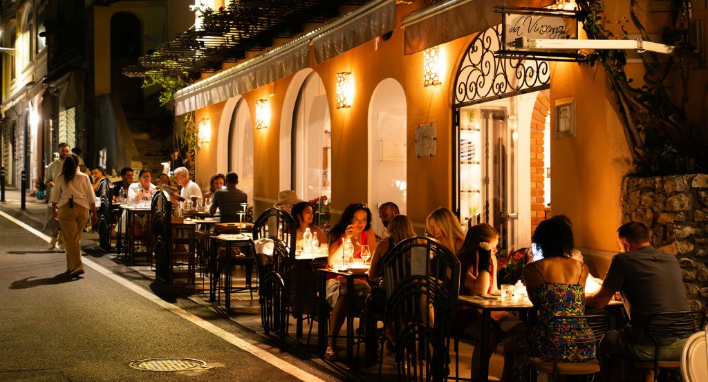 Street view of a warmly lit French bistro with guests savoring dinner outdoors