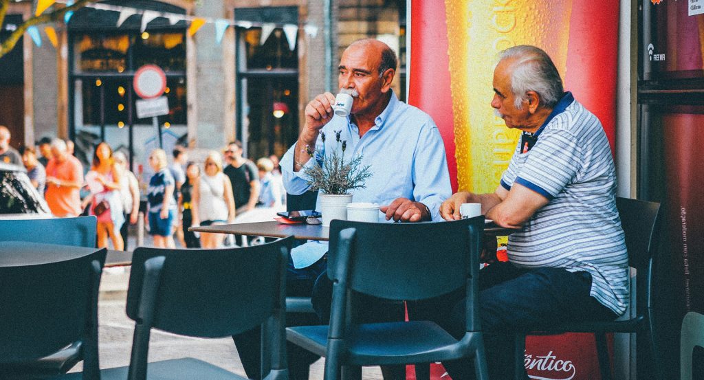 Italian men sitting at a street café, drinking coffee and talking