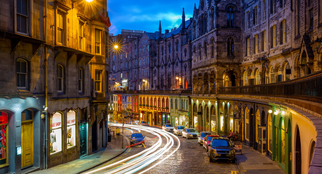 Colorful storefronts and cobbled curve of Victoria Street in Edinburgh Old Town