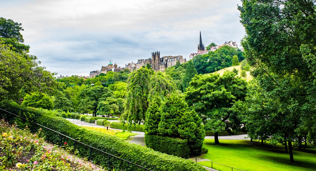 Lush greenery of Princes Street Gardens with city spires rising above