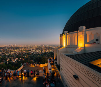 Griffith Observatory at dusk overlooking the illuminated Los Angeles skyline.