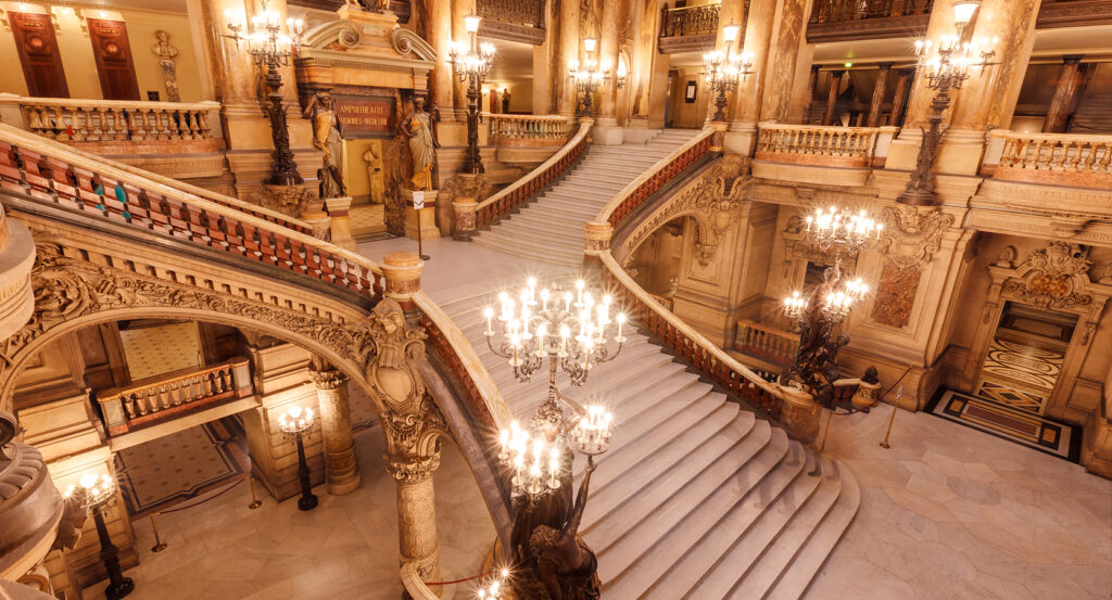 Interior view of Palais Garnier grand staircase lit by chandeliers