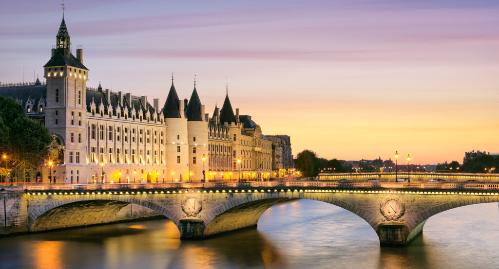 Illuminated Conciergerie and Pont Neuf reflected in the Seine at dusk