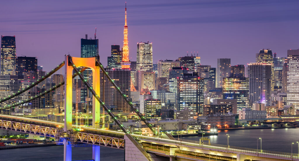 Night view of Rainbow Bridge glowing across Tokyo Bay with city skyline