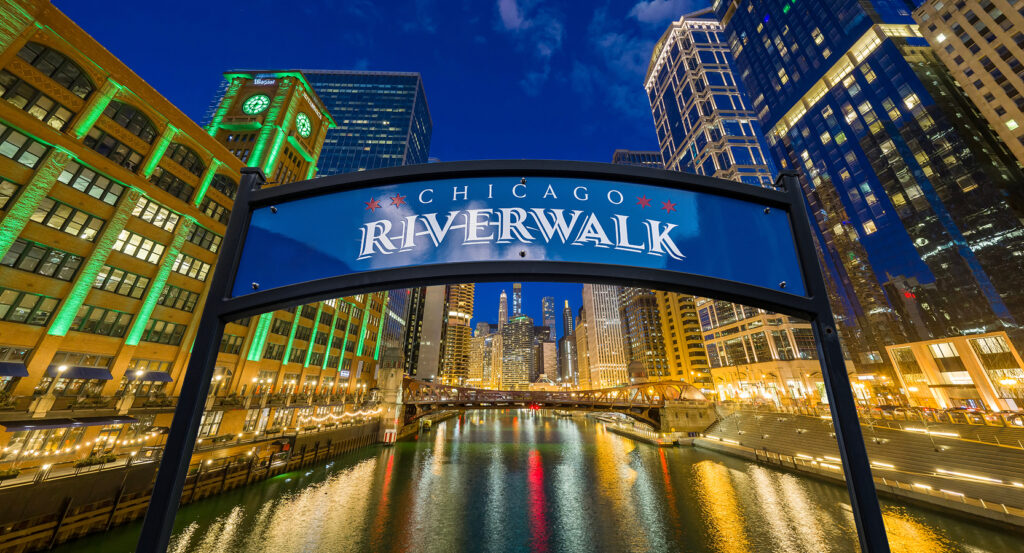 Chicago Riverwalk at night with illuminated buildings and reflections on the water