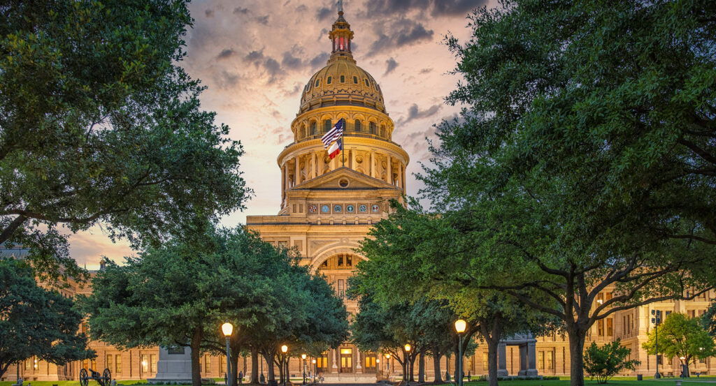 Front view of Austin’s State Capitol surrounded by green lawns