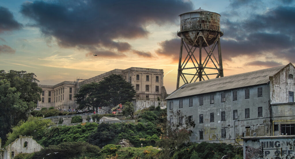 View of Alcatraz prison and decaying structures against dramatic evening sky