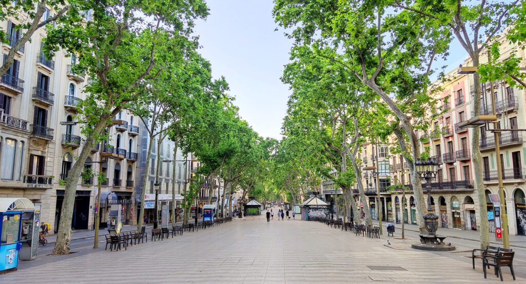 Wide pedestrian promenade of La Rambla in Barcelona with shops and cafes