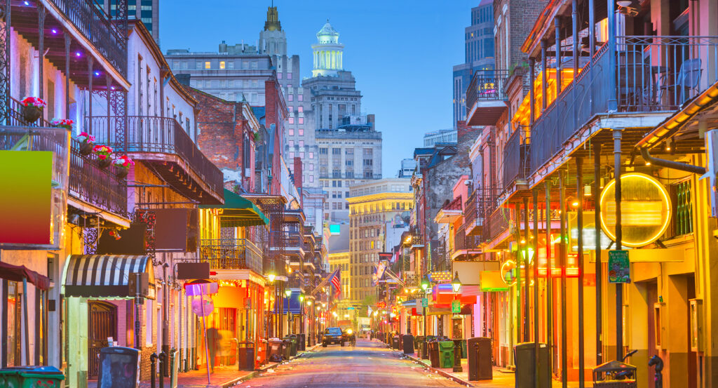 Evening view of the French Quarter with colorful lights, iron balconies, and lively atmosphere.
