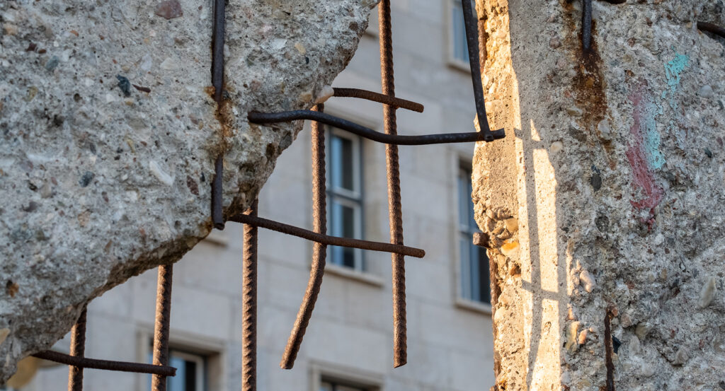 Fragment of Berlin Wall with rebar and city backdrop