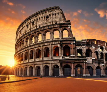 The Colosseum at sunrise in Rome, its ancient arches glowing in warm golden light under a dramatic sky.