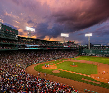Fenway Park during a Boston Red Sox game beneath dramatic evening skies in Massachusetts.