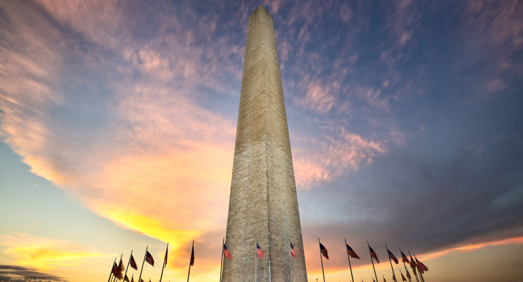 Washington Monument in Washington DC surrounded by flags under a dramatic evening sky