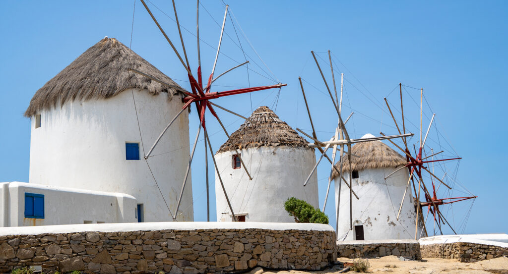 Iconic Mykonos windmills of Kato Mili with blue sky and sea view.