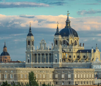 Almudena Cathedral in Madrid at sunset with a soft sky and detailed stone façade.