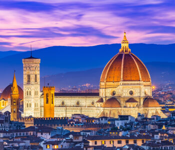 Florence’s Duomo glowing at dusk with its iconic red dome rising above the city skyline.