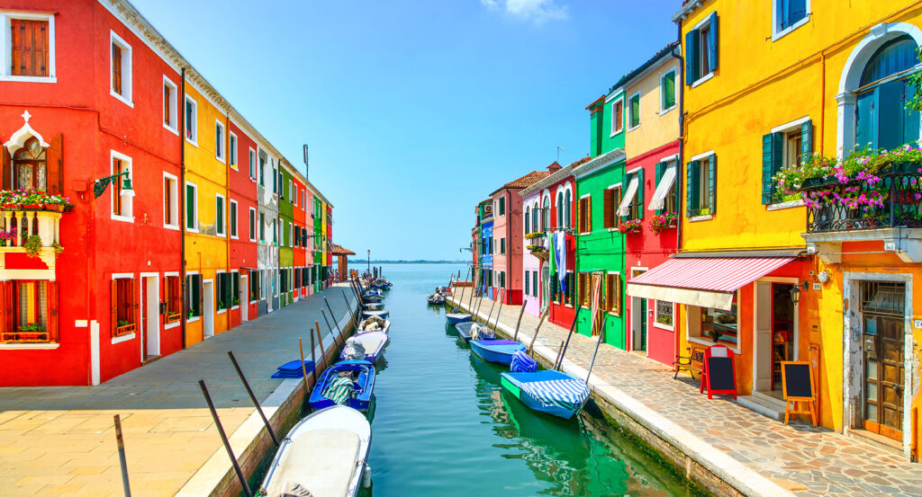 Gondolas moored by bright façades on Murano Island in Venice