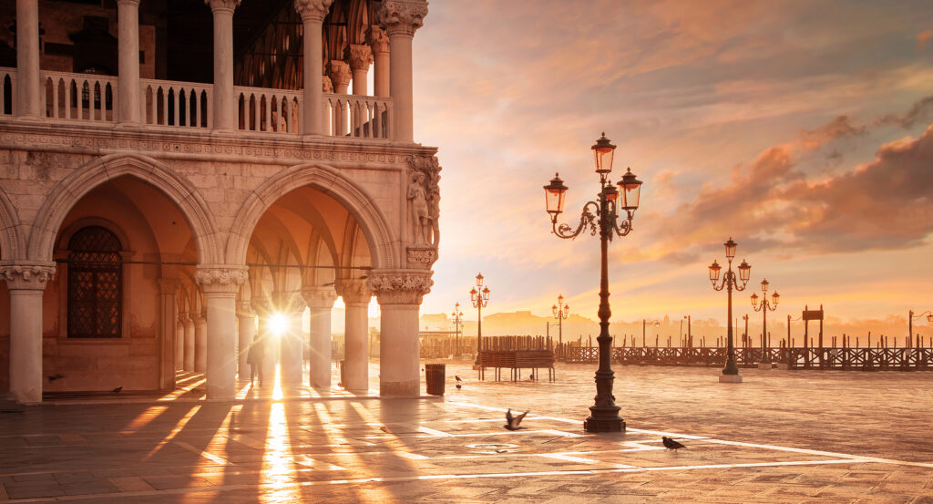 Golden hour view of St Mark’s Square with long shadows and lampposts in Venice