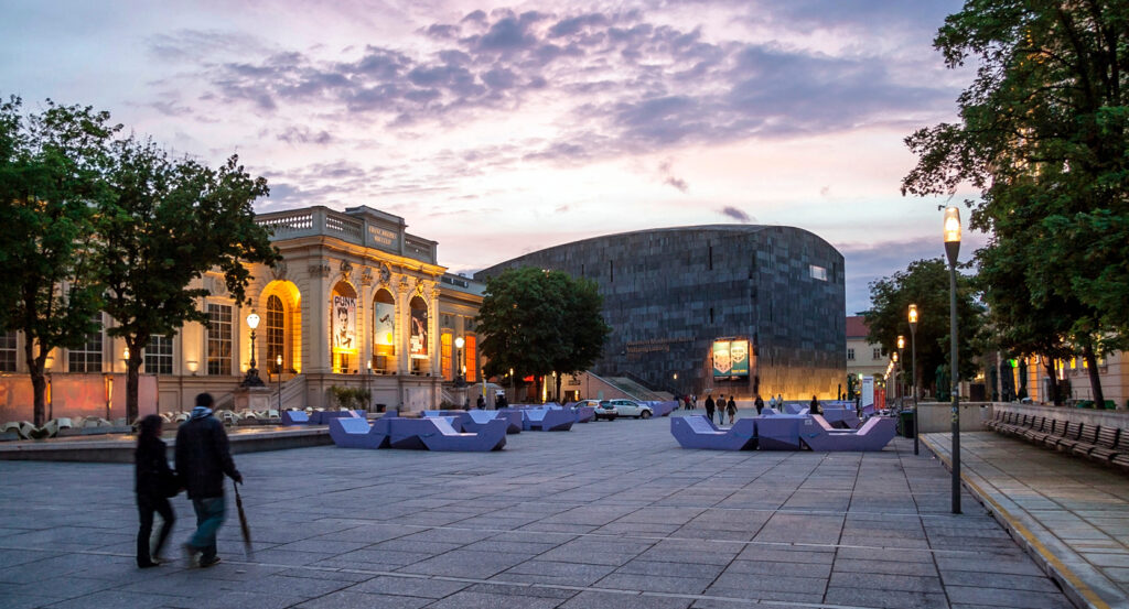 Courtyard of MuseumsQuartier Vienna with modern loungers and cultural buildings at dusk