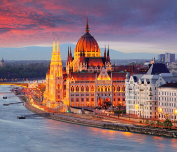 Hungarian Parliament Building glowing at sunset beside the Danube River in Budapest