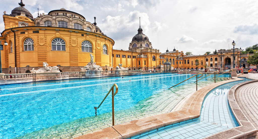 Szechenyi Thermal Bath in Budapest Hungary with steaming blue water and Neo-Baroque architecture
