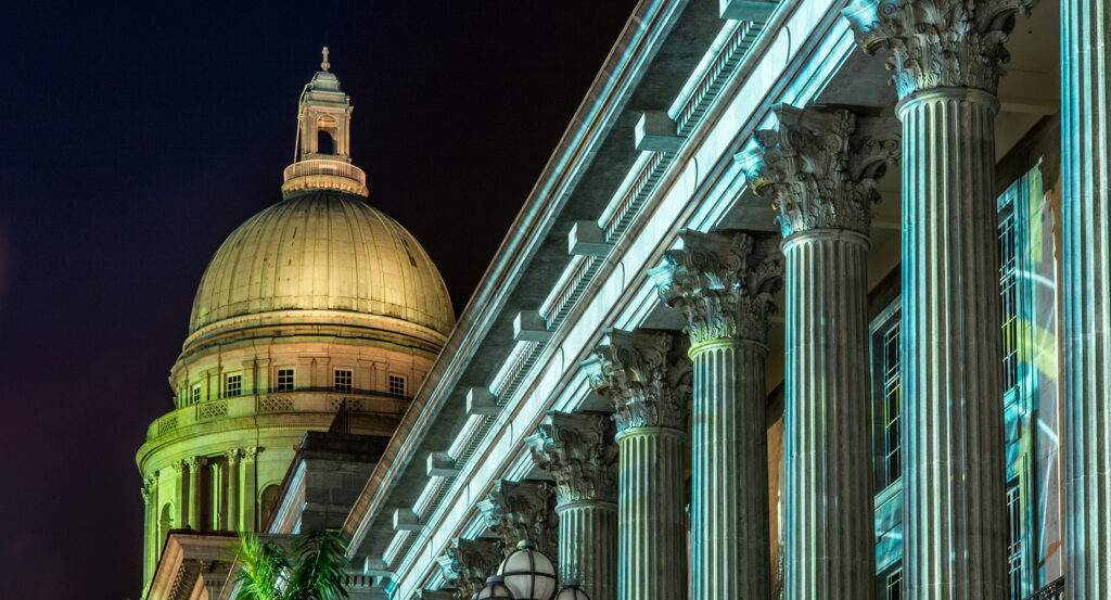 National Gallery Singapore facade with neoclassical columns lit at night
