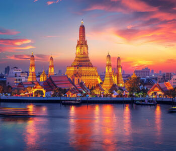 Wat Arun temple glowing at sunset along the Chao Phraya River in Bangkok
