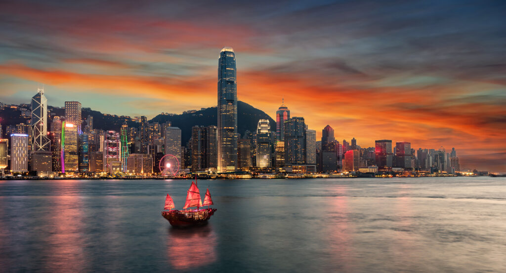 Traditional junk boat sailing Victoria Harbour at dusk