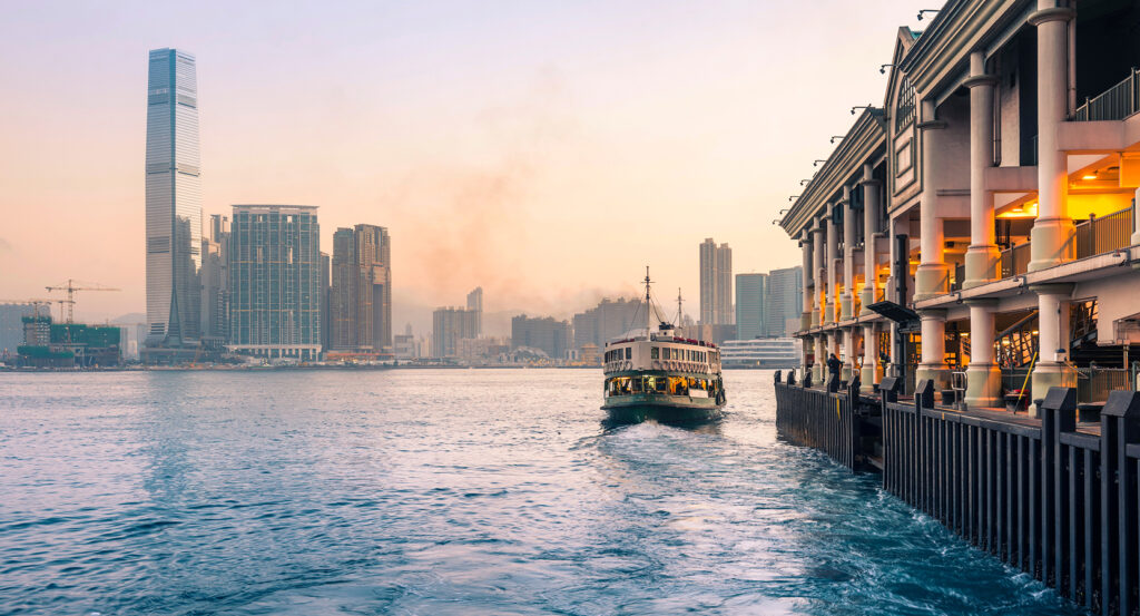 Hong Kong Star Ferry boat arriving at the pier with city skyline in background