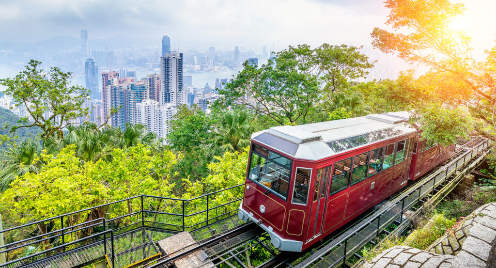 Peak Tram passing through lush greenery overlooking Hong Kong