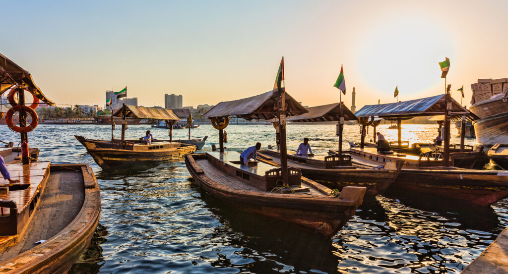 Dubai Creek waterway with boats and city skyline at dusk