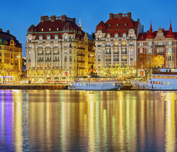 Strandvägen’s historic waterfront buildings reflected on the water at night in Stockholm.