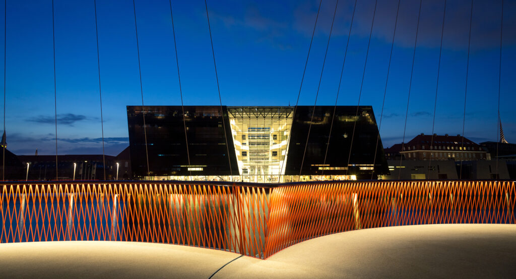 Copenhagen Royal Danish Library with glowing lights reflecting on the harbor