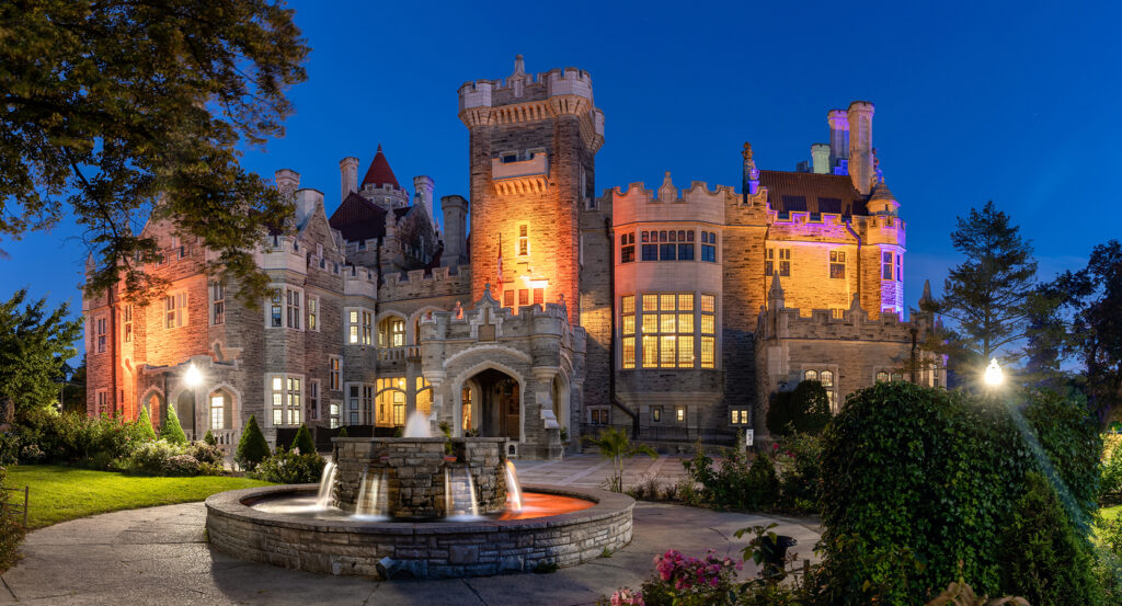 Casa Loma illuminated with colorful lights at dusk