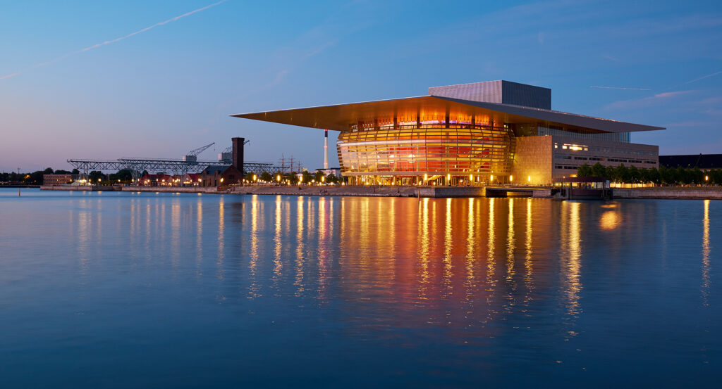 Night view of Copenhagen Opera House glowing with golden lights