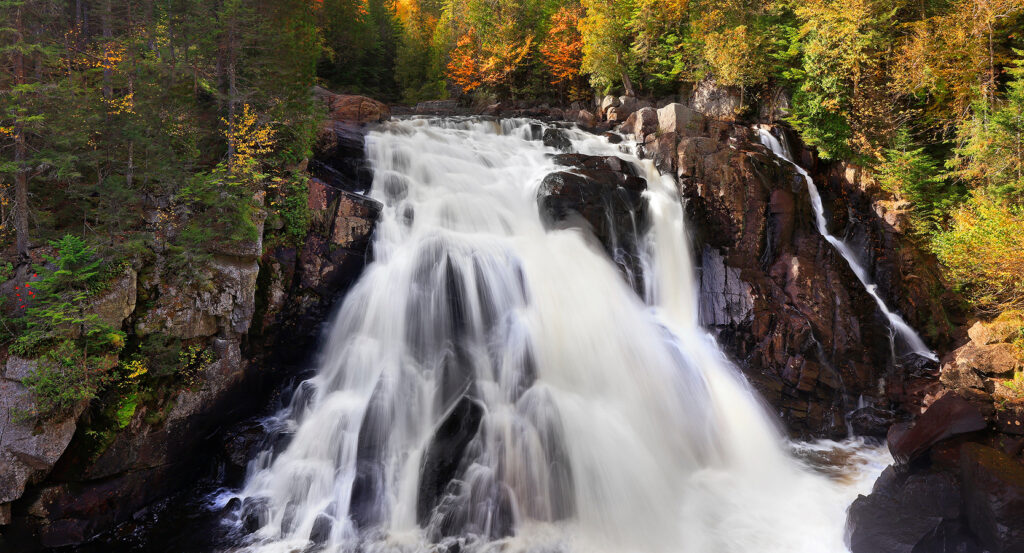View of Chute du Diable waterfall surrounded by autumn forest in Mont-Tremblant