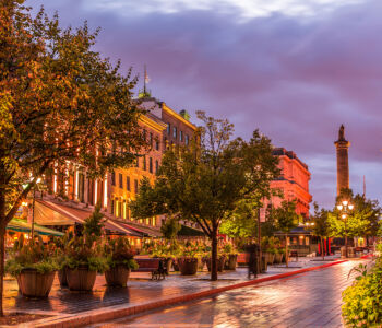 Place Jacques-Cartier illuminated at blue hour with historic buildings, lanterns, and glowing wet cobblestones.