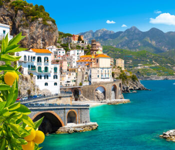 Amalfi Coast cliffside town with pastel buildings, blue water, and lemon trees in the foreground