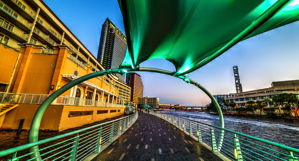 Scenic view of the Tampa Riverwalk with city skyline and waterfront in the evening.