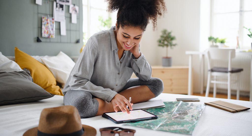 Happy female traveler using tablet for trip planning at home