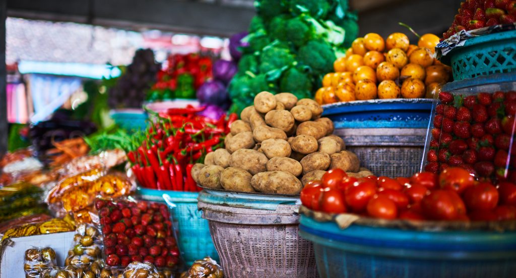 Colorful fruits and vegetables on display at a bustling Balinese street market, highlighting the textures and hues of local ingredients.