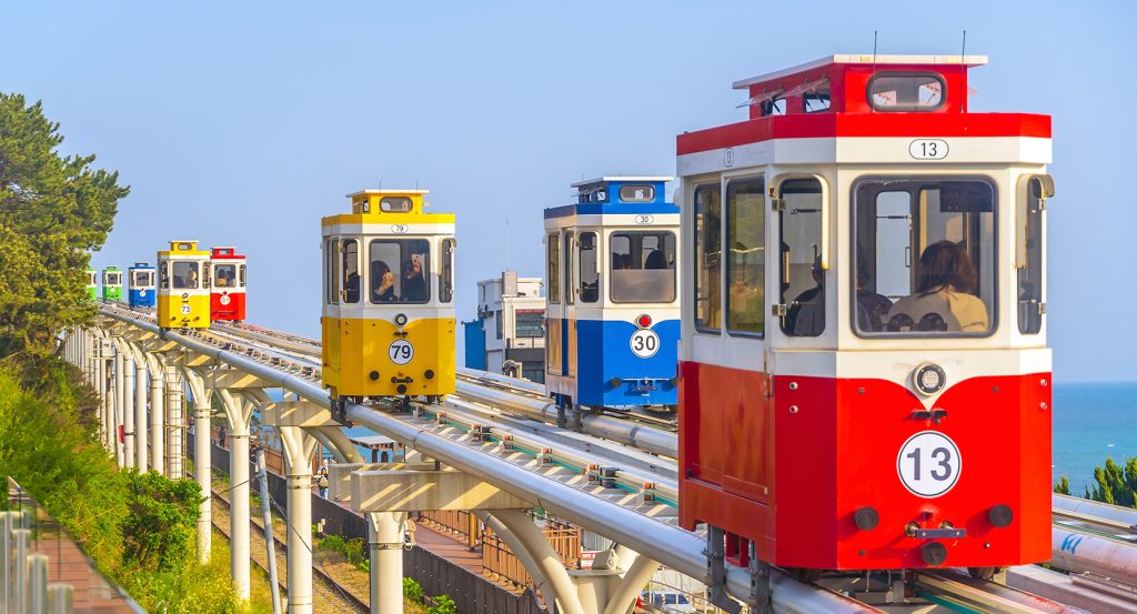 Colorful trains ride the scenic track above the sea in Busan, South Korea