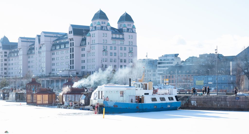 Scandinavian waterfront scene with historic buildings and a winter spa boat in Norway.