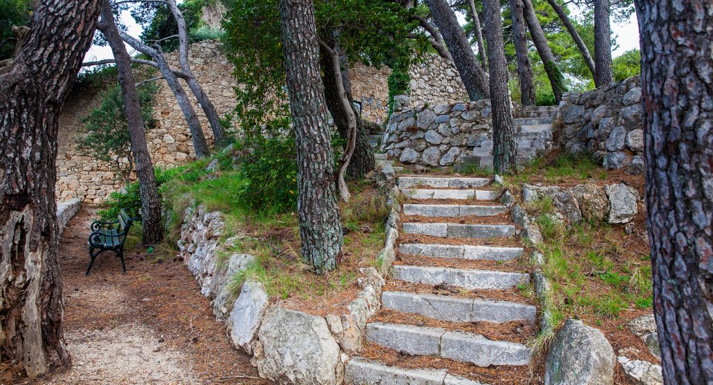 Secluded path through forested ruins near old fortress walls in Dubrovnik, Croatia.