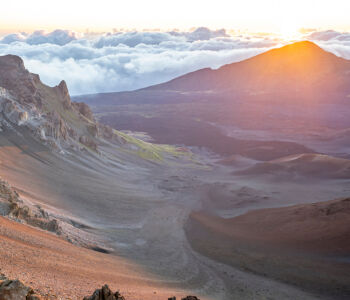 Sunrise over Haleakalā Crater with volcanic ridges and clouds blanketing the horizon near Wailea, Maui