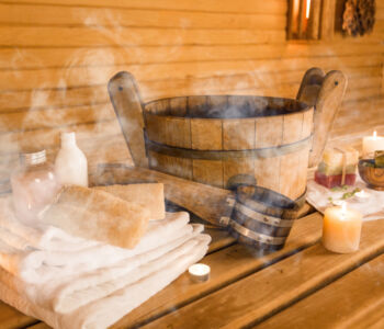 Traditional Finnish sauna with steam rising from a wooden bucket, towels, and candles.