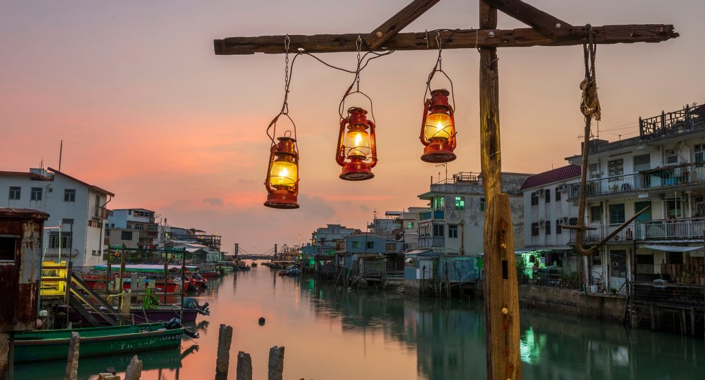 Sunset reflects off the calm canal in Tai O village, with stilt houses lining the waterway in Hong Kong.