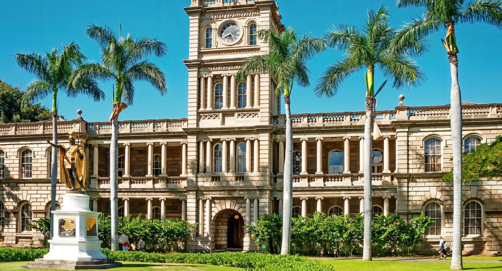Historic building and manicured grounds in downtown Honolulu on a sunny day.