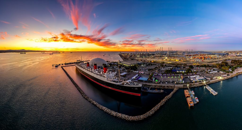 The Queen Mary surrounded by harbor lights and colorful skies in Long Beach, California.
